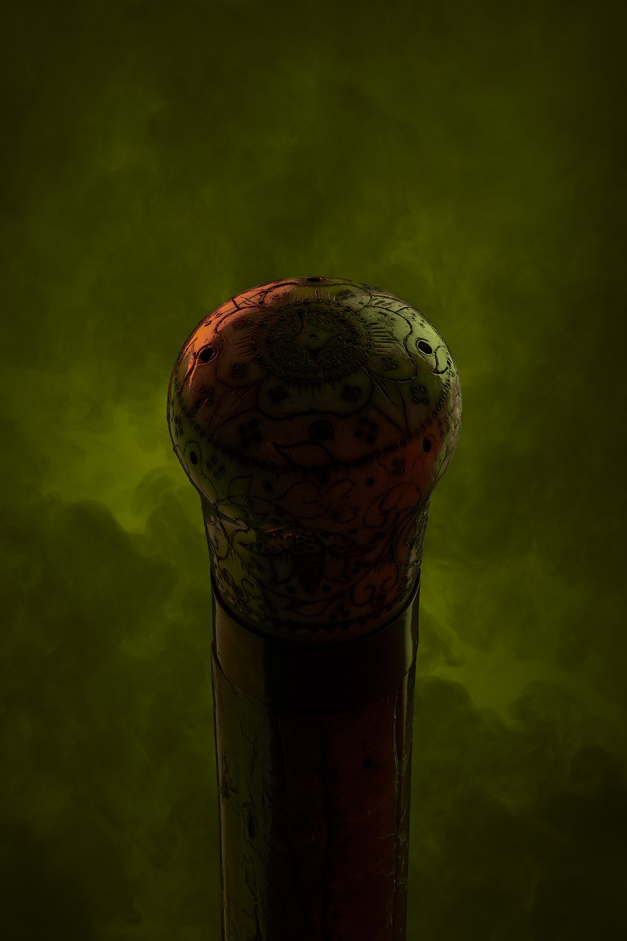 Mysterious item with bulbous end on dark green smoky background