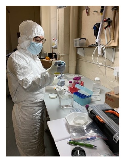Photograph of a scientist wearing protective equipment in a lab.