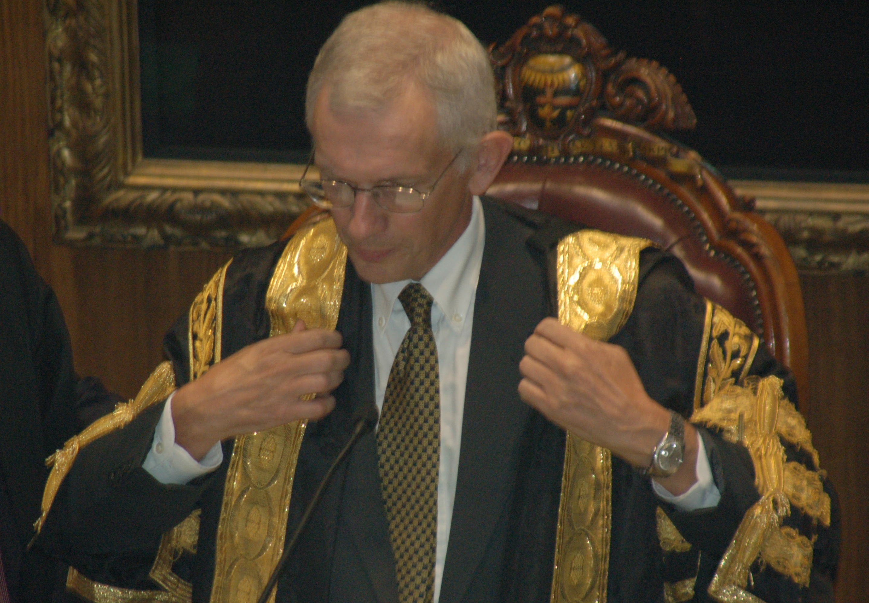 Photograph of Ian Gilmore putting on president's gown for the first time.