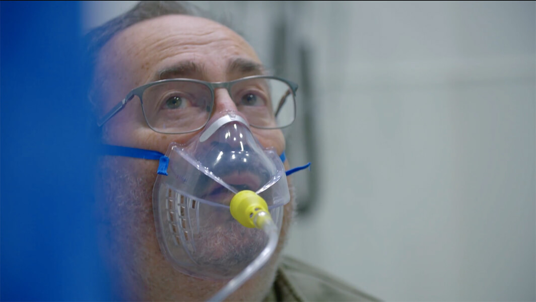 Screenshot of a doctor wearing an oxygen mask.