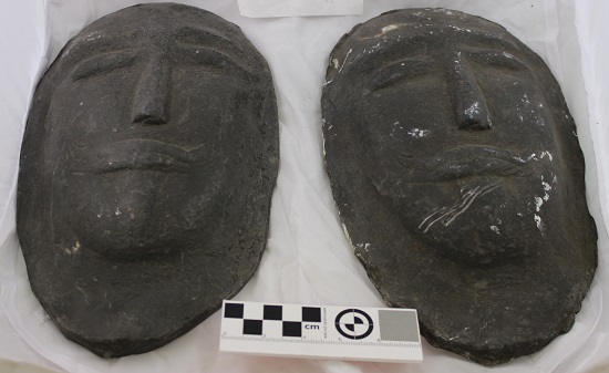 Two metal plaques in the form of death masks.
