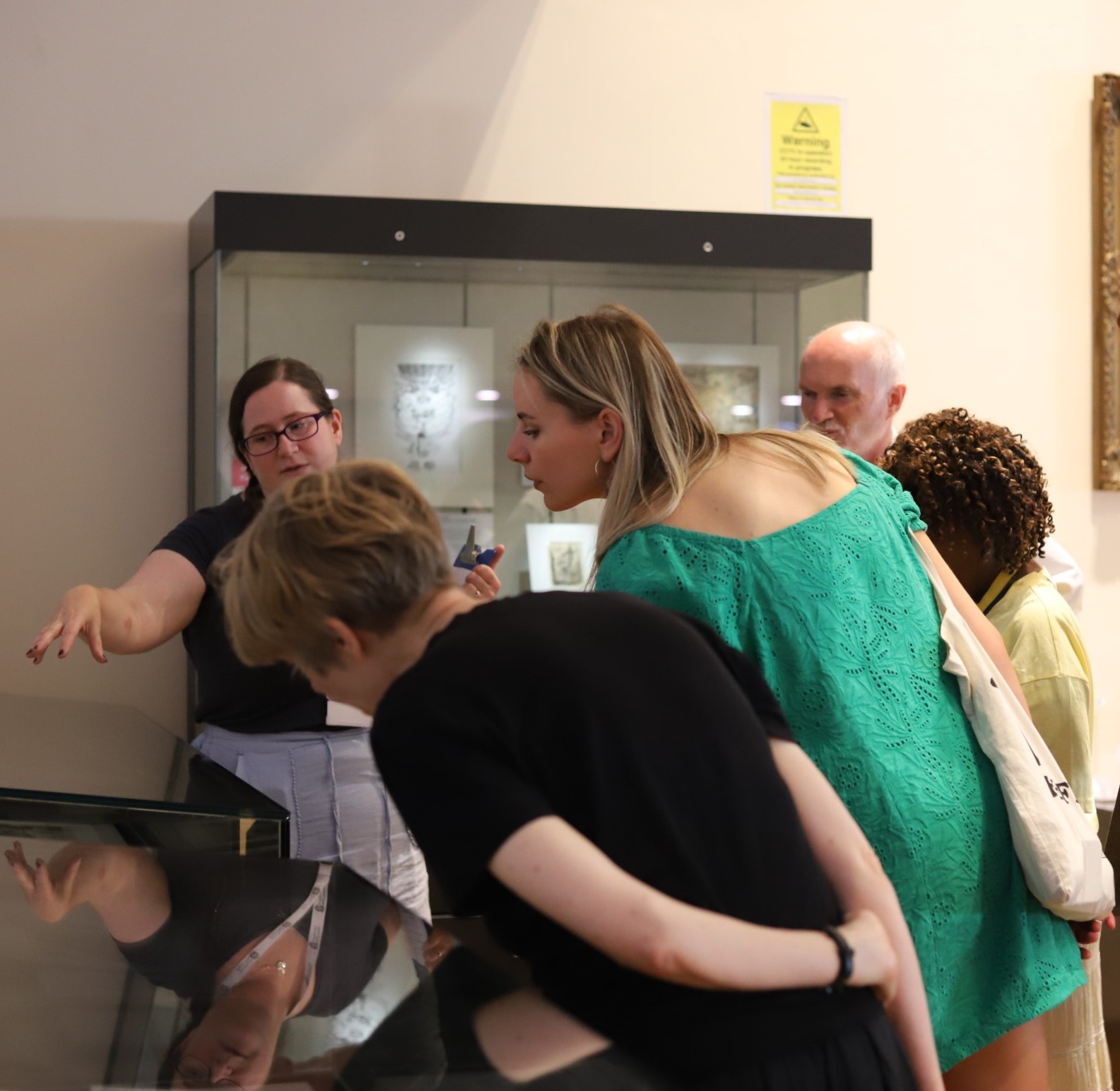 Visitors lean over a display case.