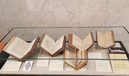 Photograph of early printed books on display in a glass case