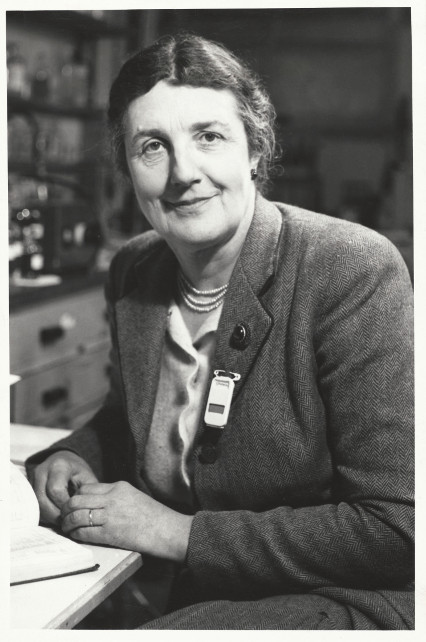 Black and white photographic portrait of a woman sat in a lab.