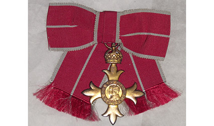 Colour photograph of a gold, cross-shaped medal with red ribbon