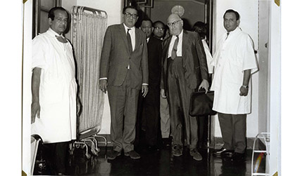Black and white photograph of four men standing in a hospital, two are wearing white coats